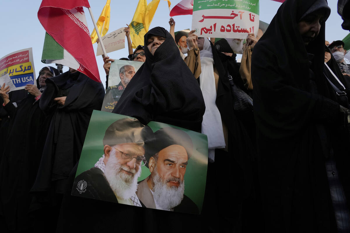 An Iranian woman holds a poster of the late revolutionary founder Ayatollah Khomeini, right, an ...