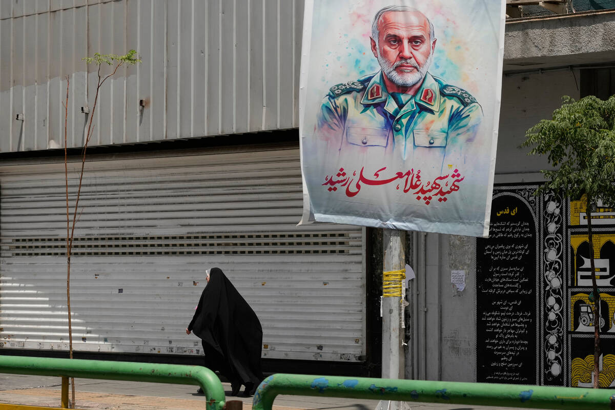 An Iranian woman walks past a banner showing head of the paramilitary Revolutionary Guard's Kha ...