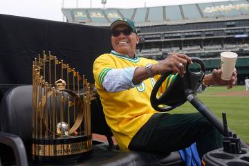 Reggie Jackson smiles while sitting next to the World Series trophy during a celebration of the ...