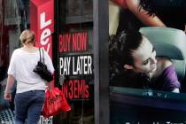 A woman walks by a sign "Buy now pay later" at a store in Bangalore, India, on Sept. 10, 2009. ...
