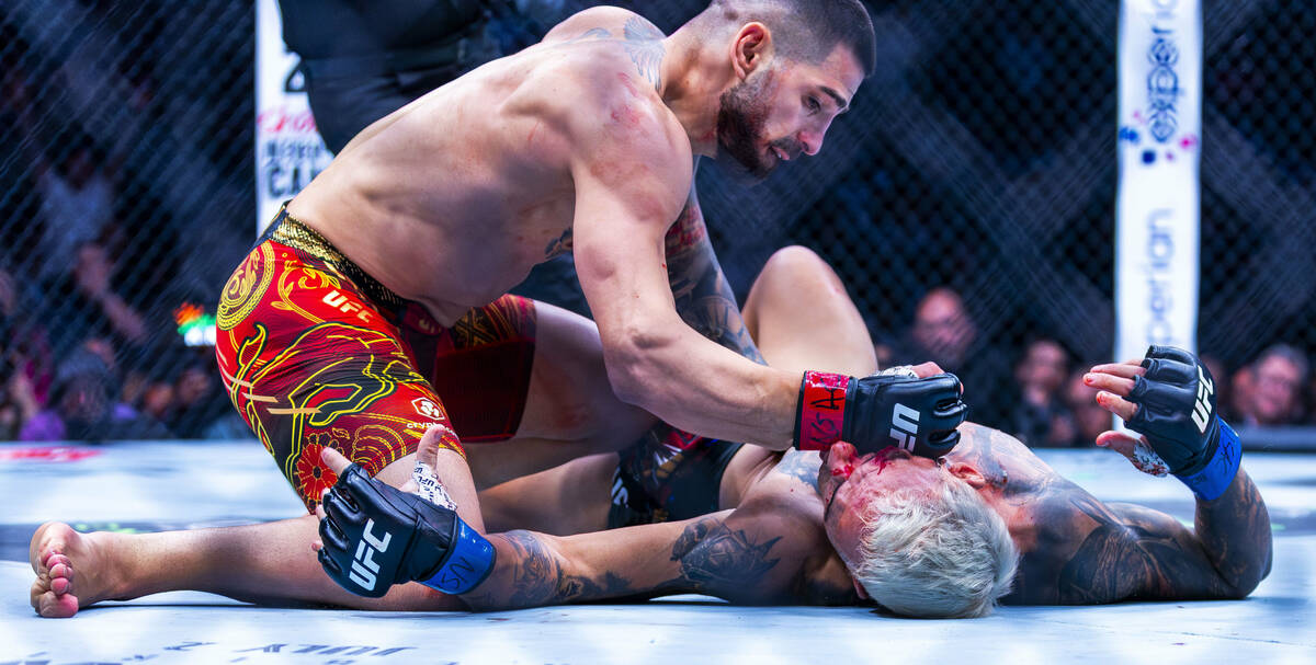 Ilia Topuria drives a fist into the face of Charles Oliveira already knocked down and out on th ...