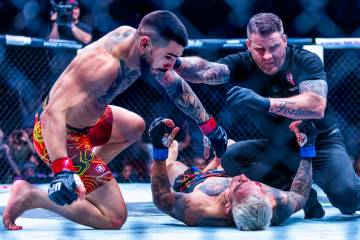 Ilia Topuria is pushed off of Charles Oliveira already knocked down and out on the canvas durin ...