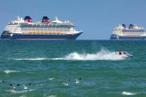 Jet skiers pass the Disney Cruise Line ships "Fantasy," left, and "Dream" on the horizon as the ...