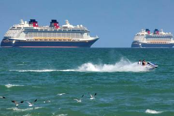 Jet skiers pass the Disney Cruise Line ships "Fantasy," left, and "Dream" on the horizon as the ...