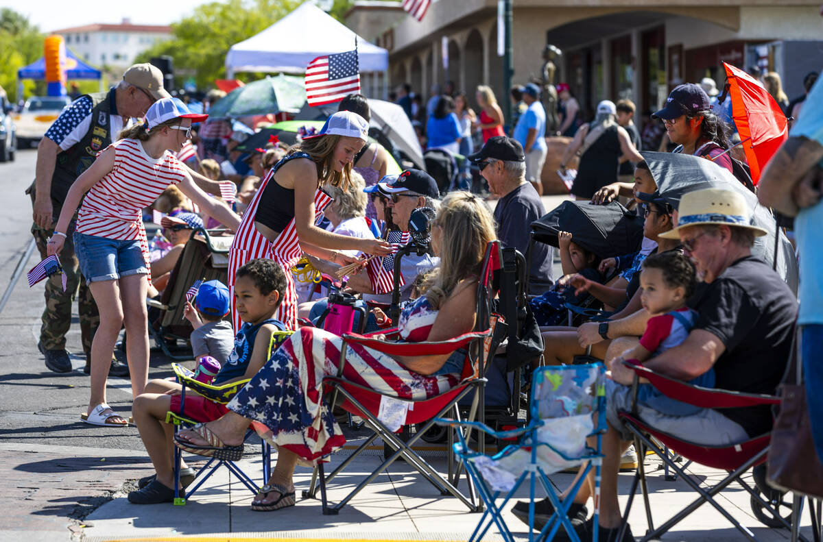 Flags are passed out by the American Legion Post 31 during the parade at the 77th Annual Dambor ...