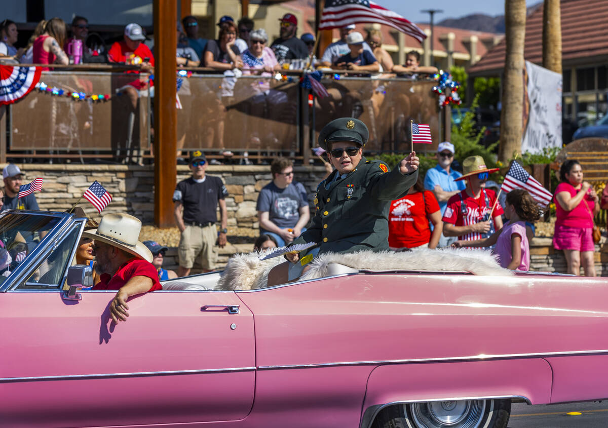 A young Elvis Presley rides in a pink Cadillac complete with uniform and flag during the parade ...