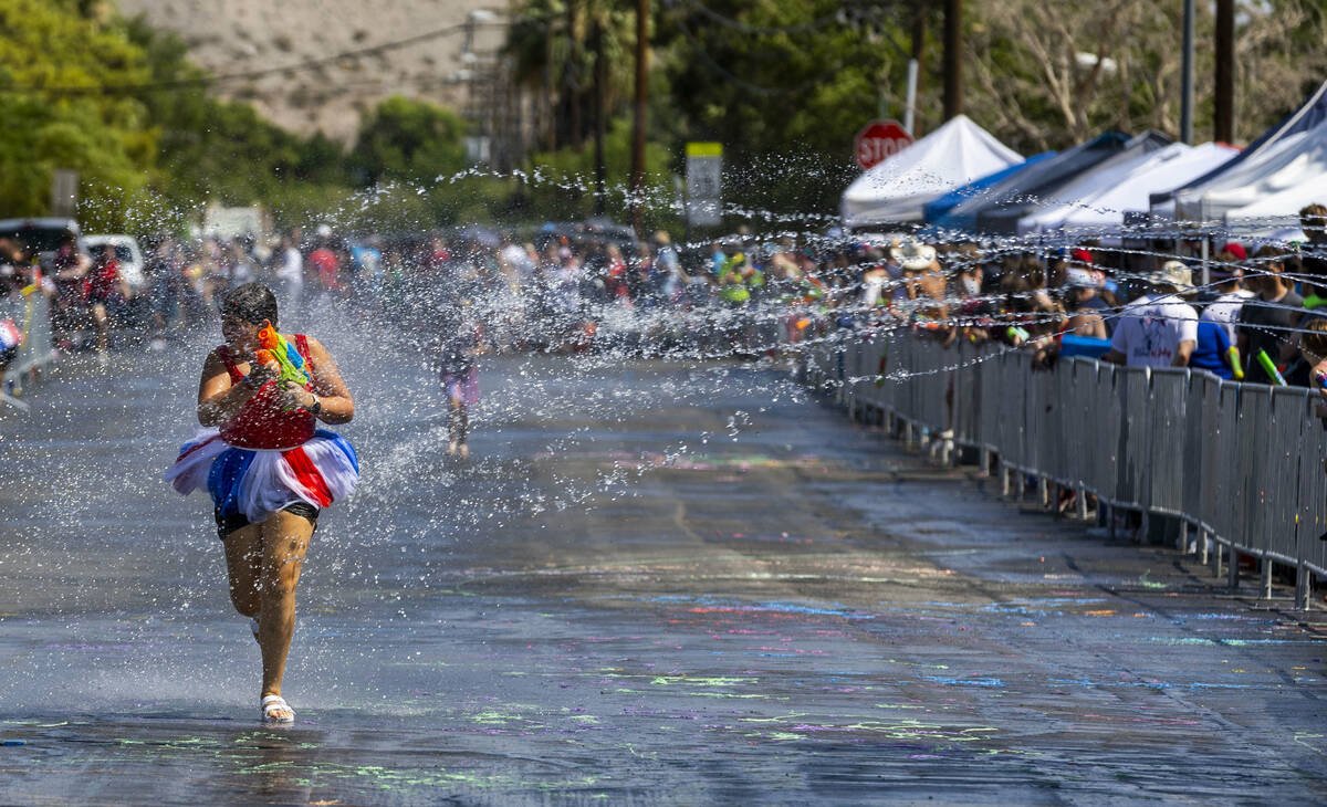 Sophia Poghossian, 14, of Henderson, is blasted with water from attendees in the "wet are ...