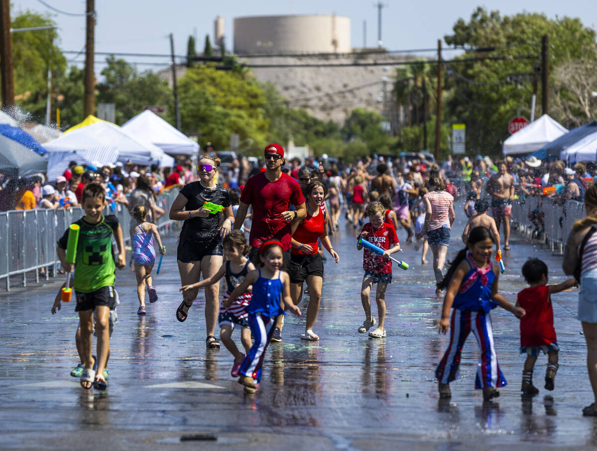 Attendees are blasted with water from others in the "wet area" section of the parade ...