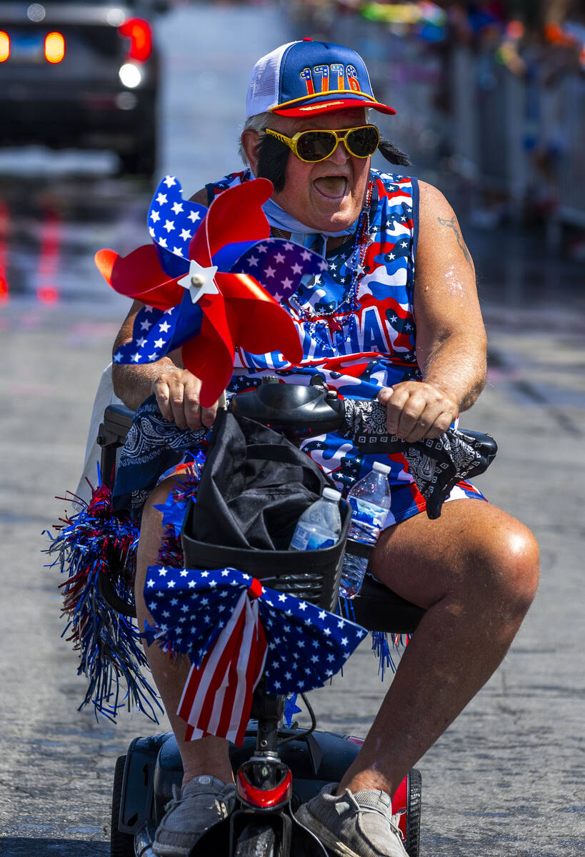 An attendee with Elvis get up evades being sprayed with water as he makes his way along the par ...
