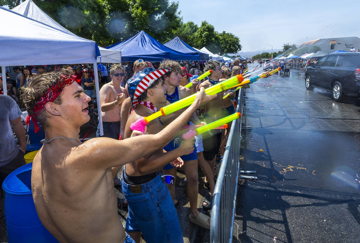 Attendees fire straps of water at passing floats in the "wet area" section of the par ...