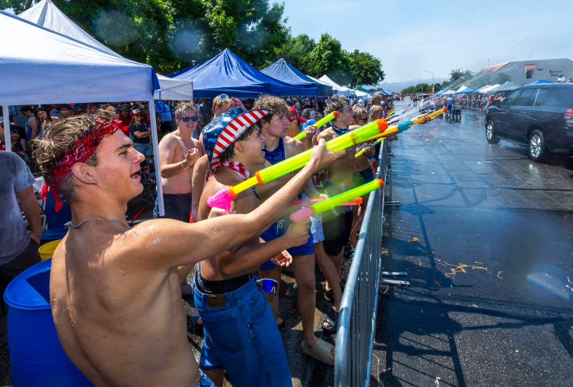 Attendees fire straps of water at passing floats in the "wet area" section of the par ...