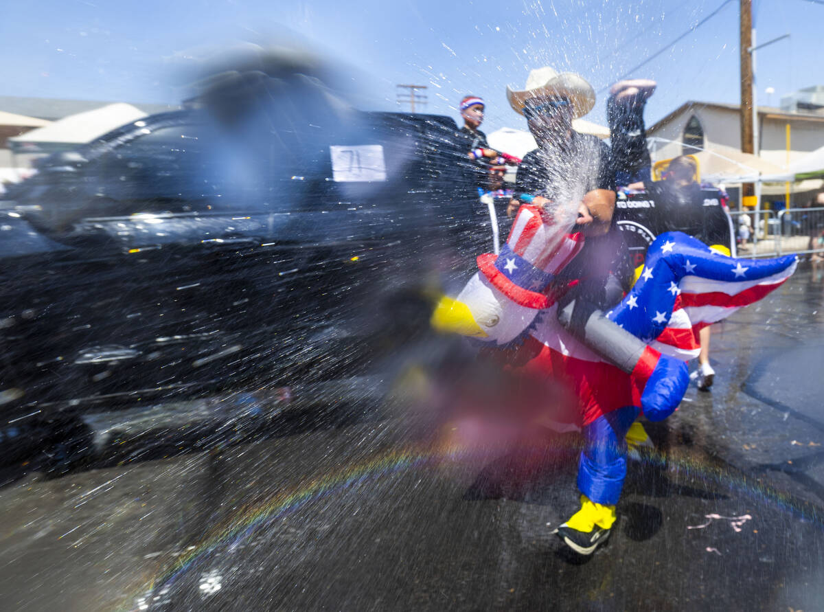 A participant in in an eagle costume sprays attendees in the "wet area" section of th ...