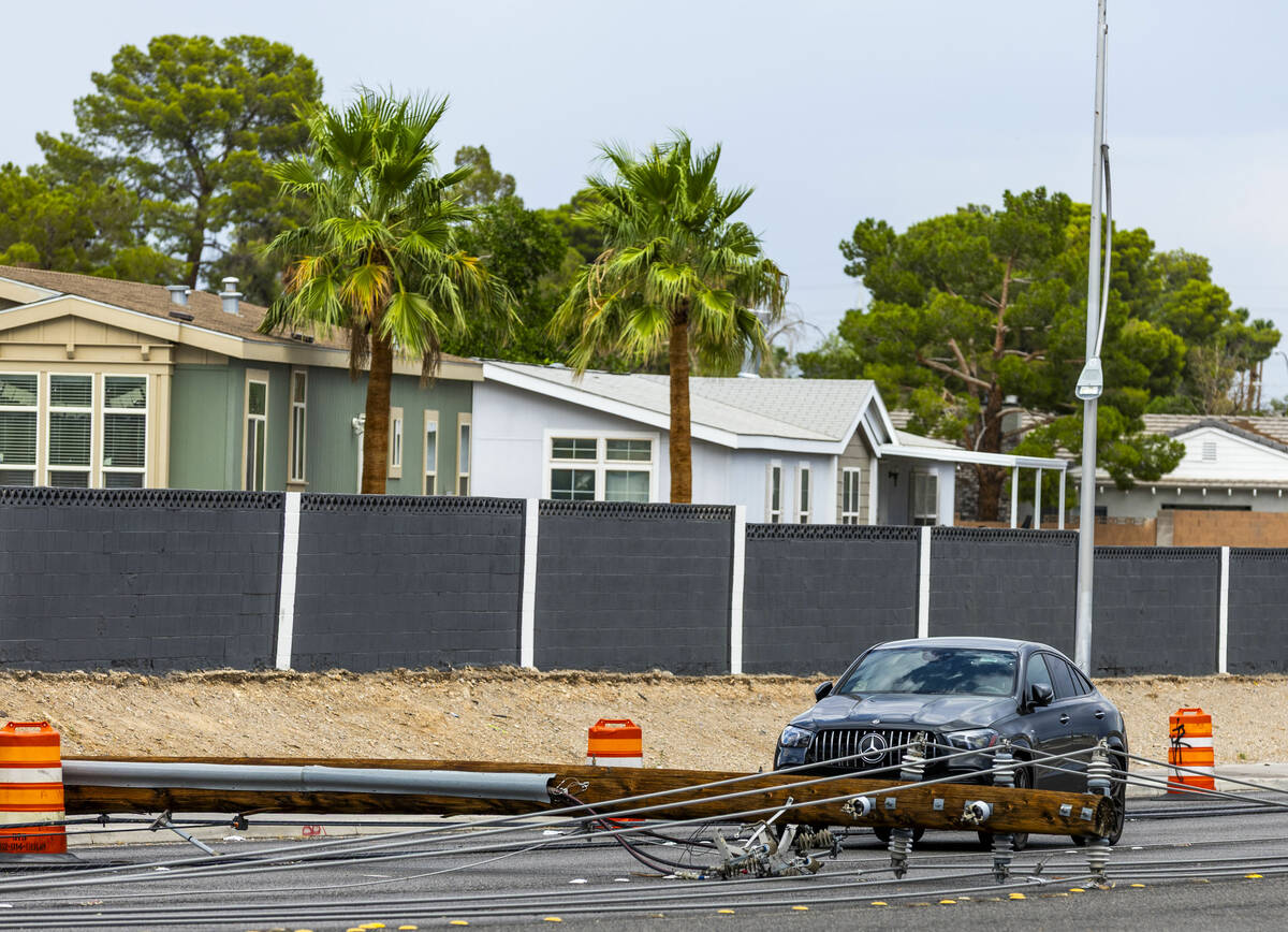 A Mercedes is stuck between downed power lines as crews continue on storm damage repair along S ...