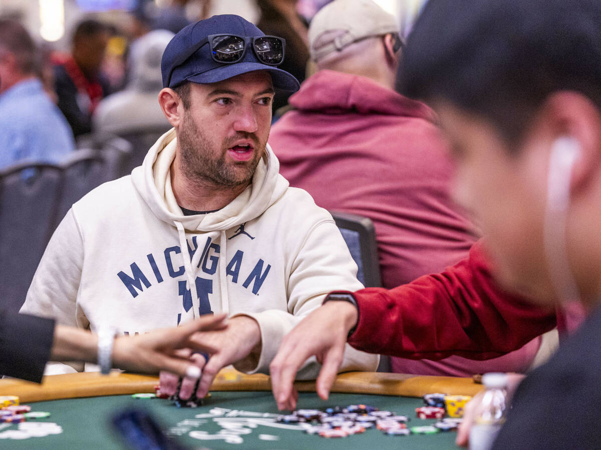 Professional poker player Joe Cada talks with a competitor at his table during opening day of t ...
