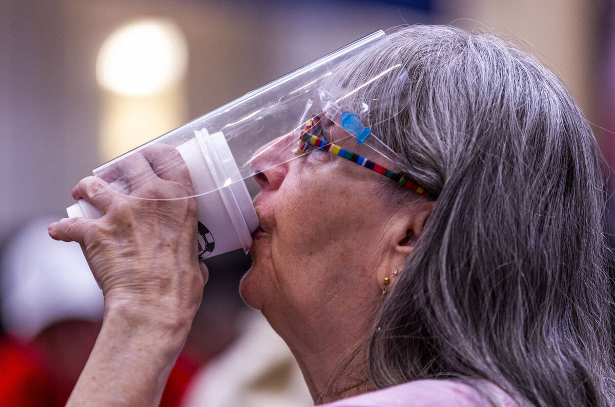 A player enjoys a drink while staying germ free behind a mask during opening day of the WSOP Ma ...