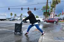A pedestrian navigates rain runoff on Sahara Avenue after a storm Thursday, July 3, 2025, in La ...
