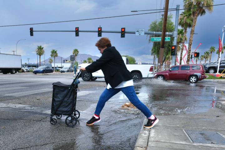 A pedestrian navigates rain runoff on Sahara Avenue after a storm Thursday, July 3, 2025, in La ...