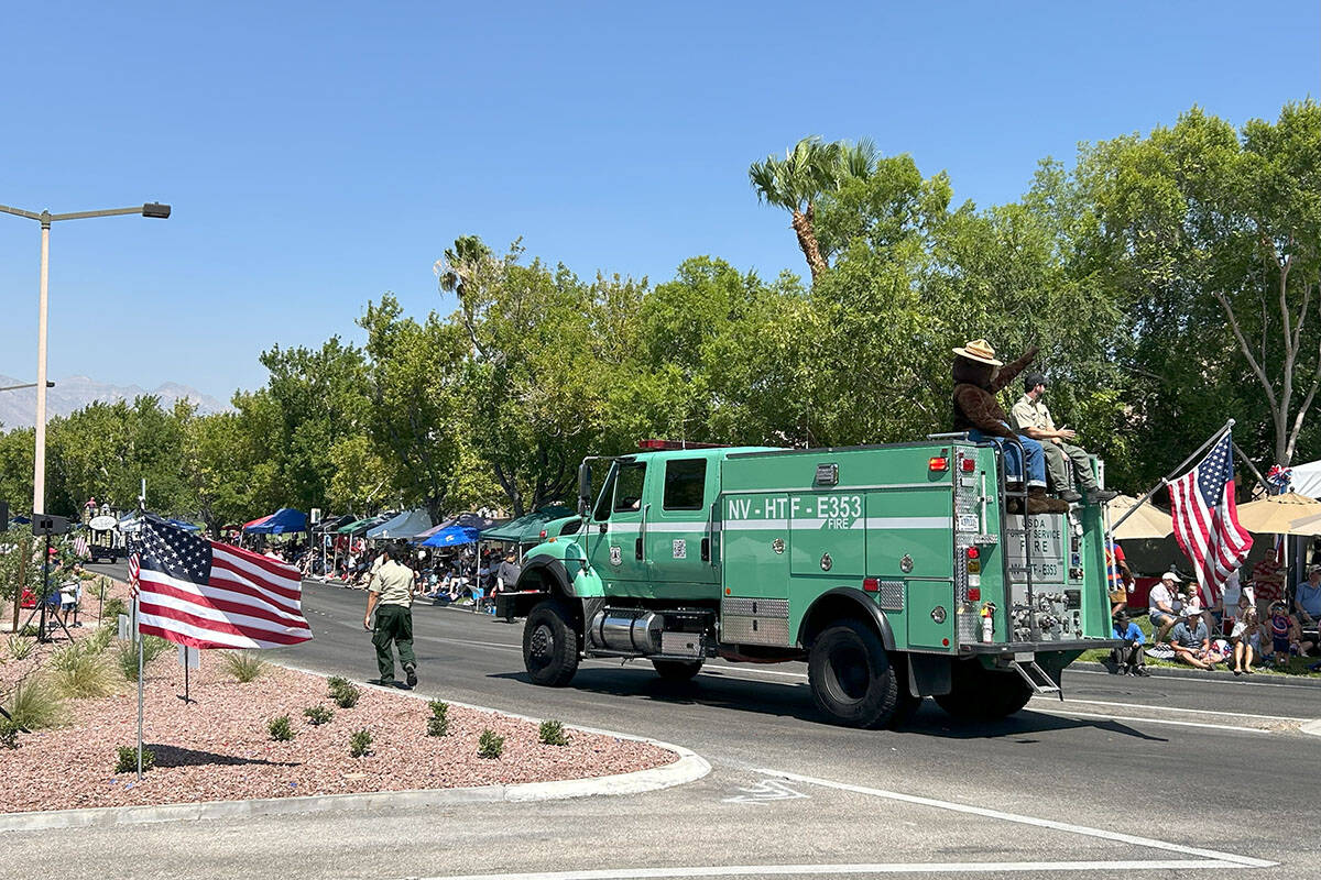 Smokey Bear waves to parade onlookers while riding on a National Forest Service truck at the Su ...