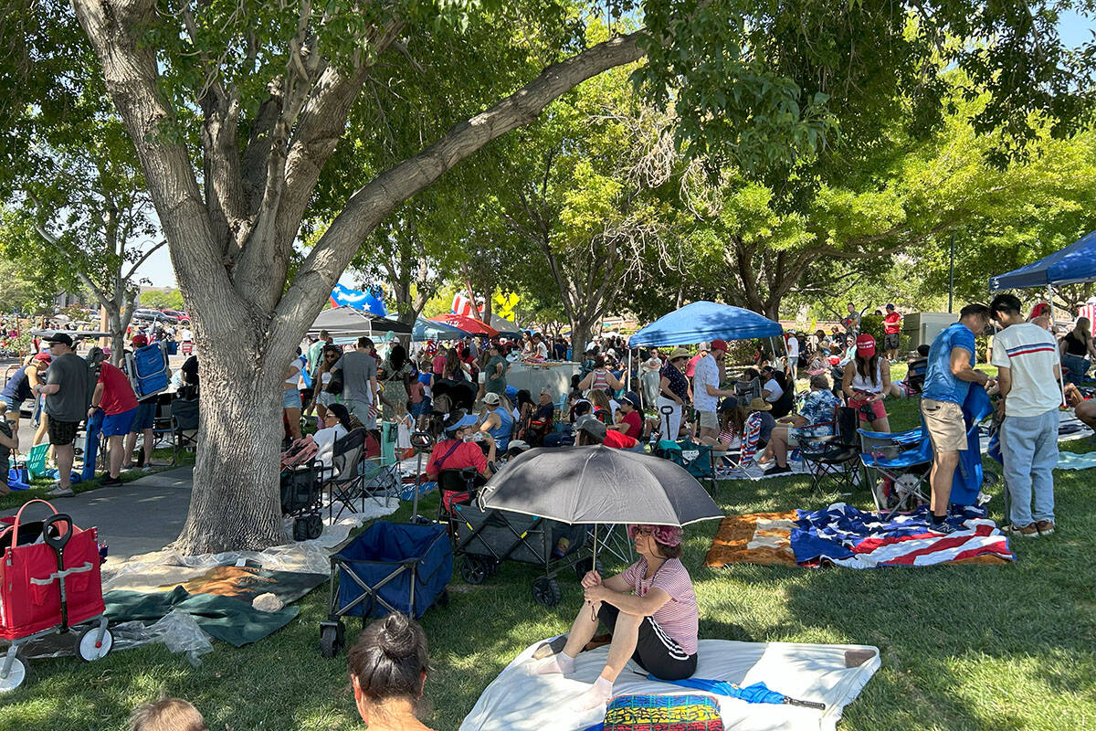 Parade attendees sit on the grass along the Summerlin Patriotic Parade's route on Friday, July ...