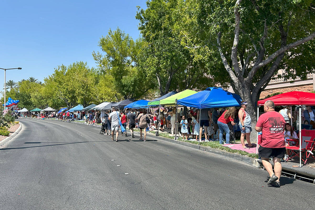 Parade attendees sit under canopies set up along the Summerlin Patriotic Parade's route on Frid ...