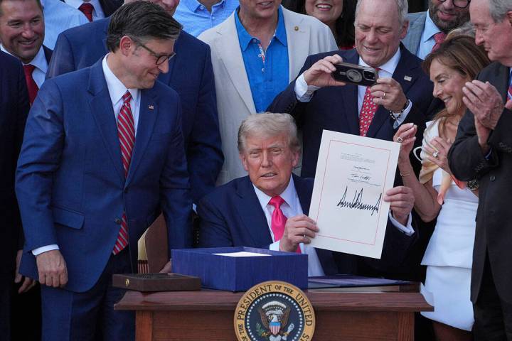 President Donald Trump holds his signed signature bill of tax breaks and spending cuts at the W ...