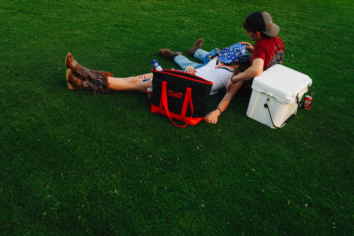 A couple relaxes in the grass during a Fourth of July bash at Heritage Park Friday, July 4, 202 ...