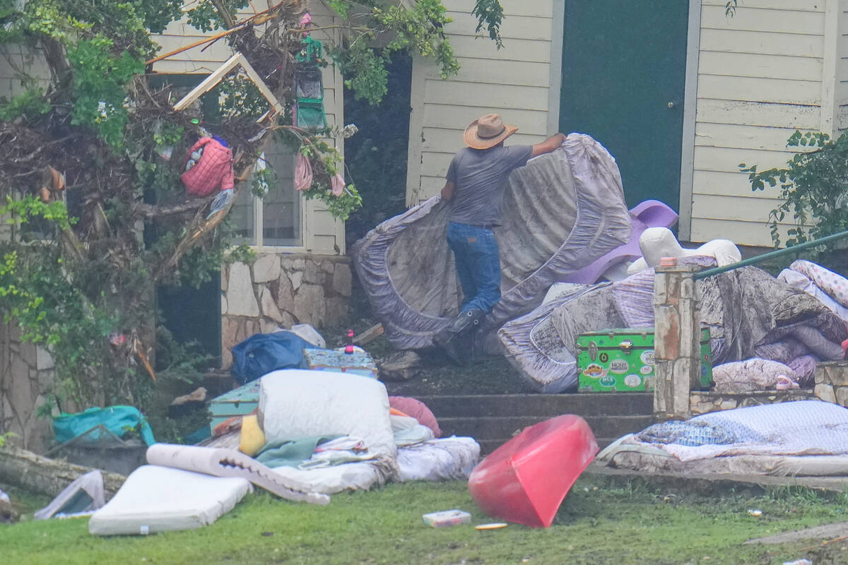 A person removes bedding from sleeping quarters at Camp Mystic along the banks of the Guadalupe ...