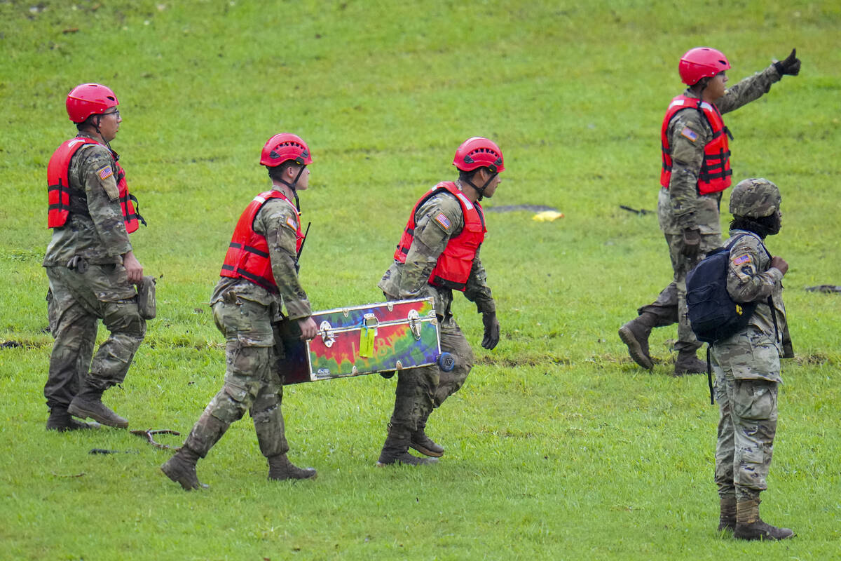 Military personnel carry a camp trunk salvaged down river from Camp Mystic along the Guadalupe ...
