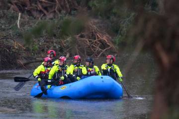 Officials ride a boat as they arrive to assist with a recovery effort at Camp Mystic along the ...