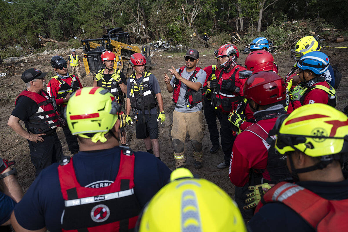 A crew of firefighters from Ciudad Acuna, Mexico, gather for a briefing as they aid in search a ...