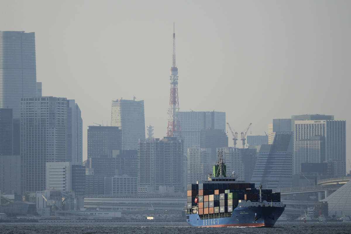 FILE - Tokyo Tower is seen amid tall buildings as a container ship leaves a cargo terminal in T ...