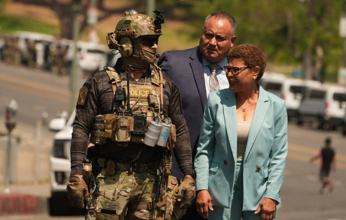 Los Angeles Mayor Karen Bass walks with a federal agent at MacArthur Park Monday, July 7, 2025, ...