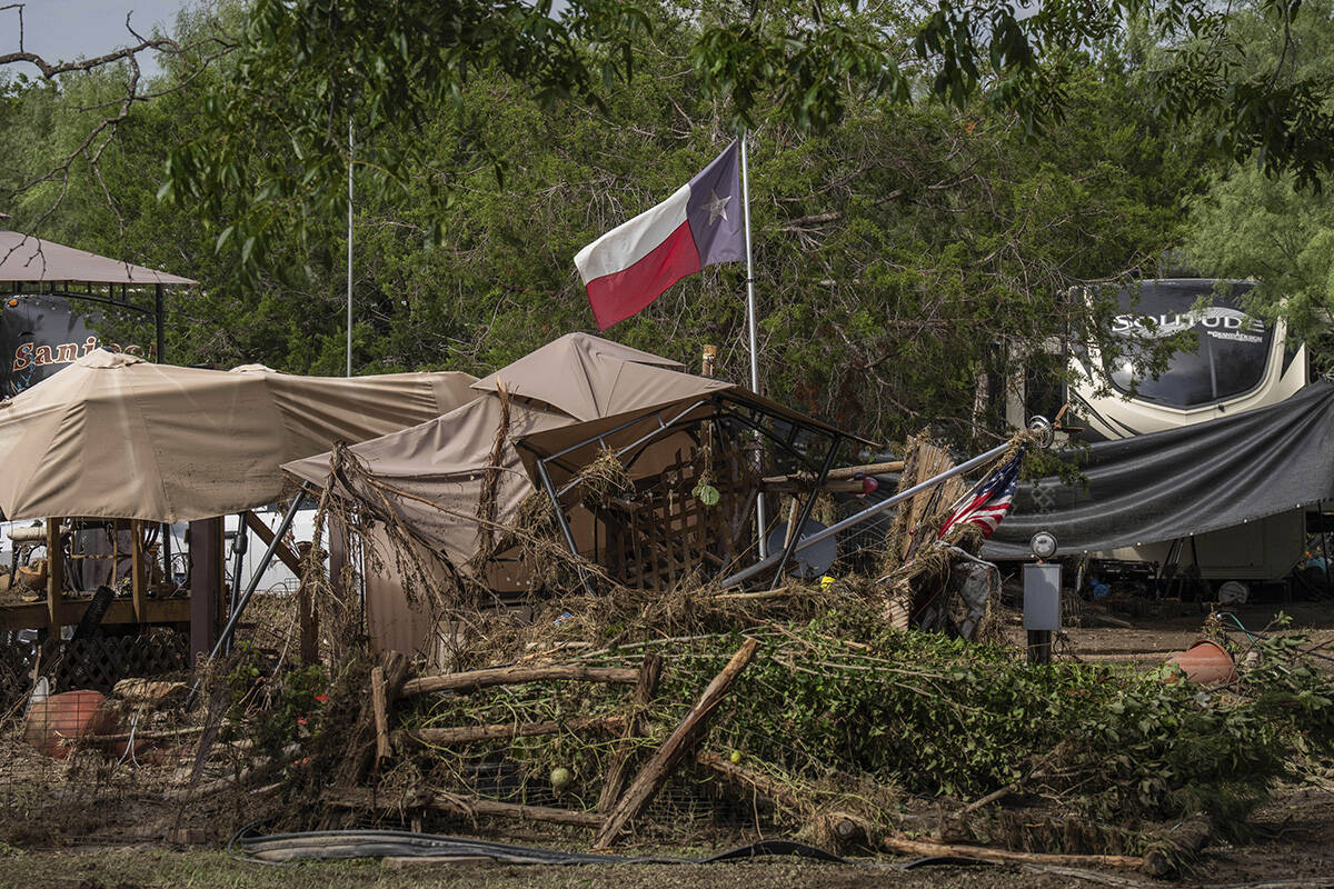A Texas flag waves in the wind amongst debris from flash flooding at Cedar Stays RV Park in Mar ...