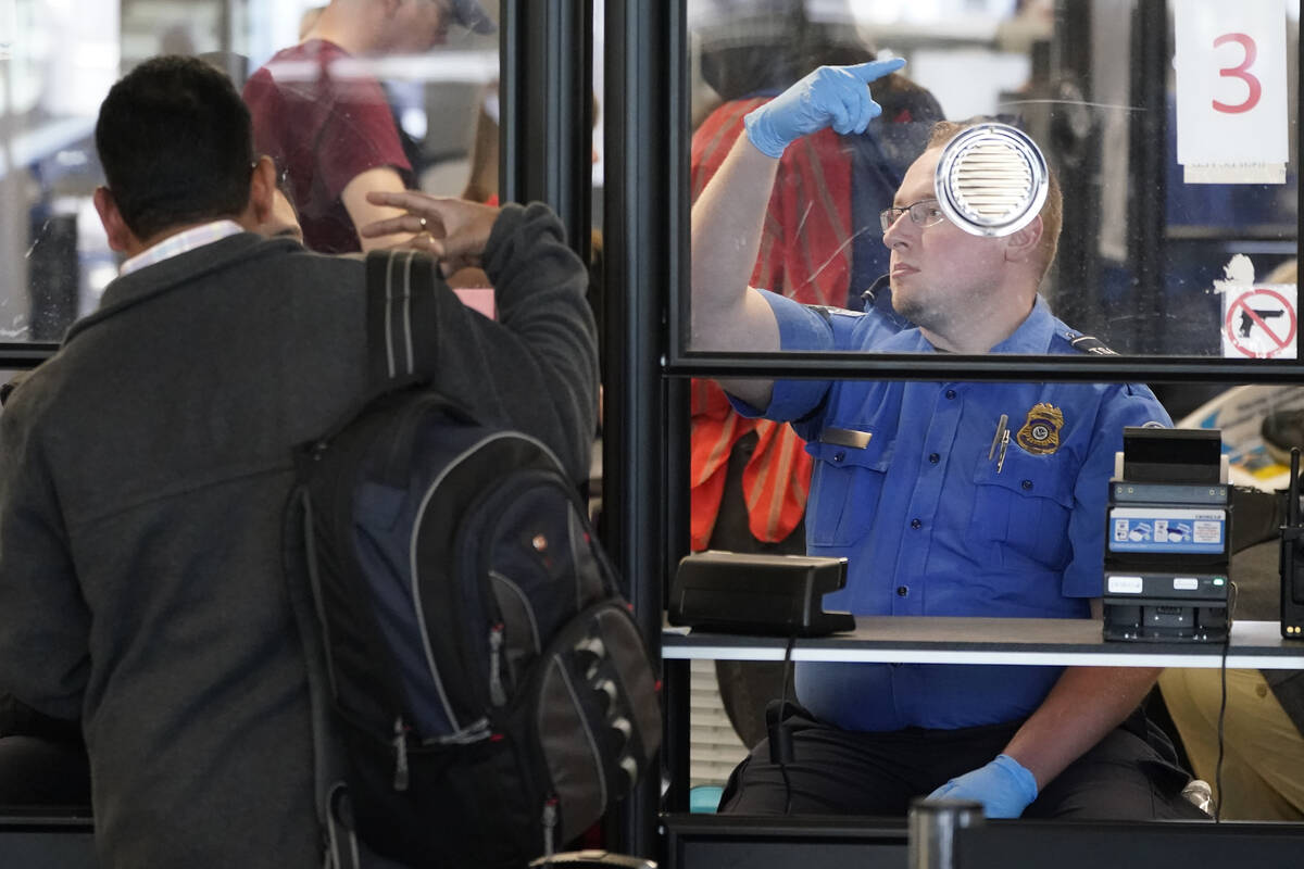 A Transportation Security Administration agent signals for the next airline passenger in line a ...