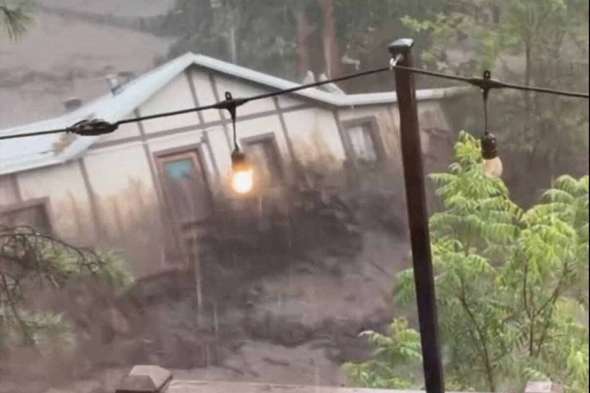 In this image taken from video, a house is carried away by flash flooding behind a house in Rui ...
