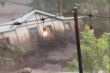 In this image taken from video, a house is carried away by flash flooding behind a house in Rui ...