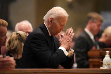 Former US President Joe Biden kneels in prayer during funeral services for Mark and Melissa Hor ...