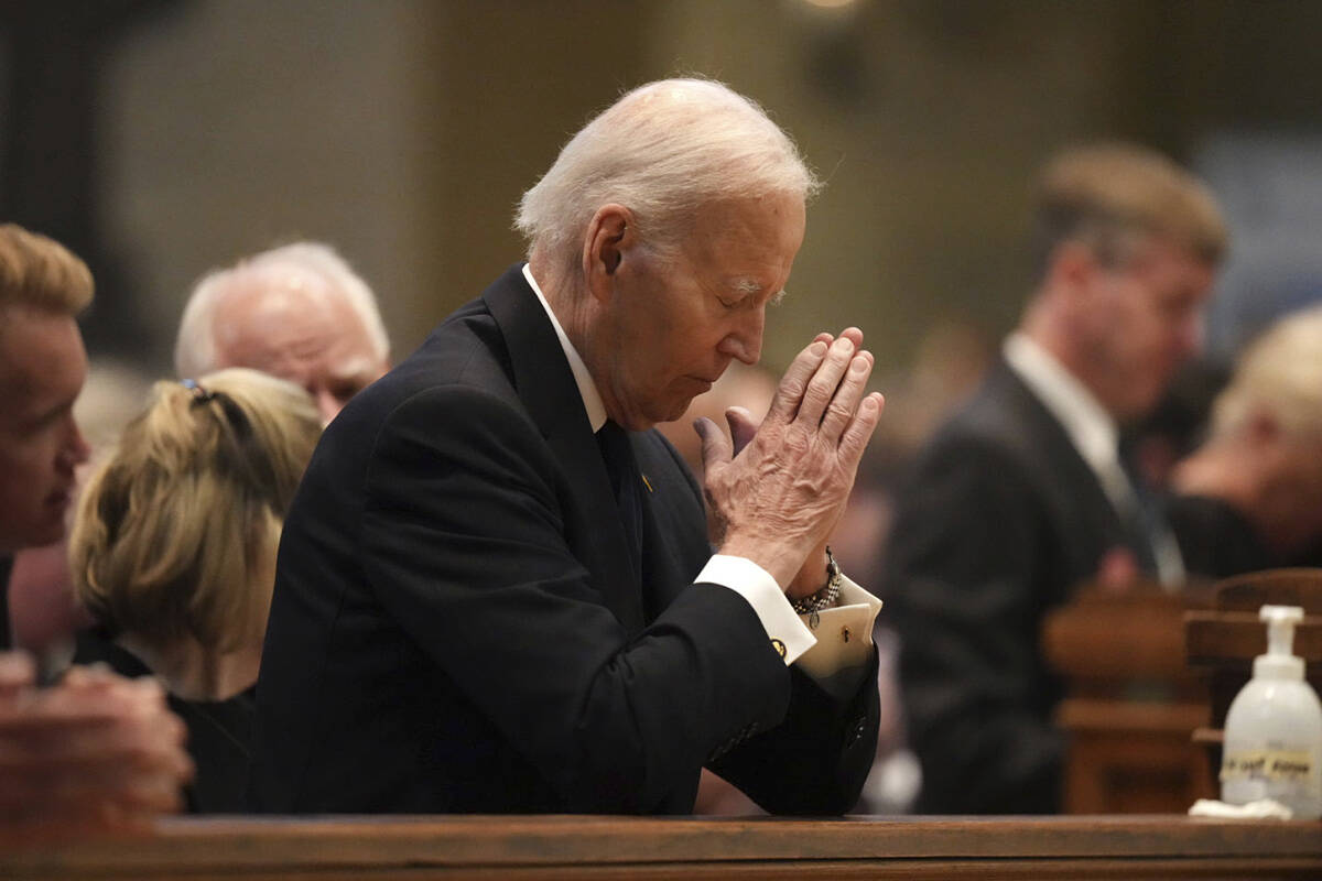 Former US President Joe Biden kneels in prayer during funeral services for Mark and Melissa Hor ...