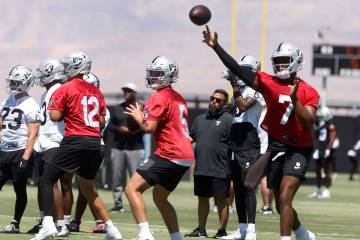Raiders quarterback Geno Smith (7) throws the ball as quarterbacks Aidan O'Connell (12) and Ca ...