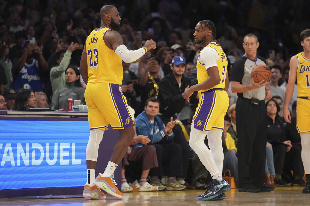 Los Angeles Lakers forward LeBron James (23) and guard Bronny James (9) stand on the court duri ...
