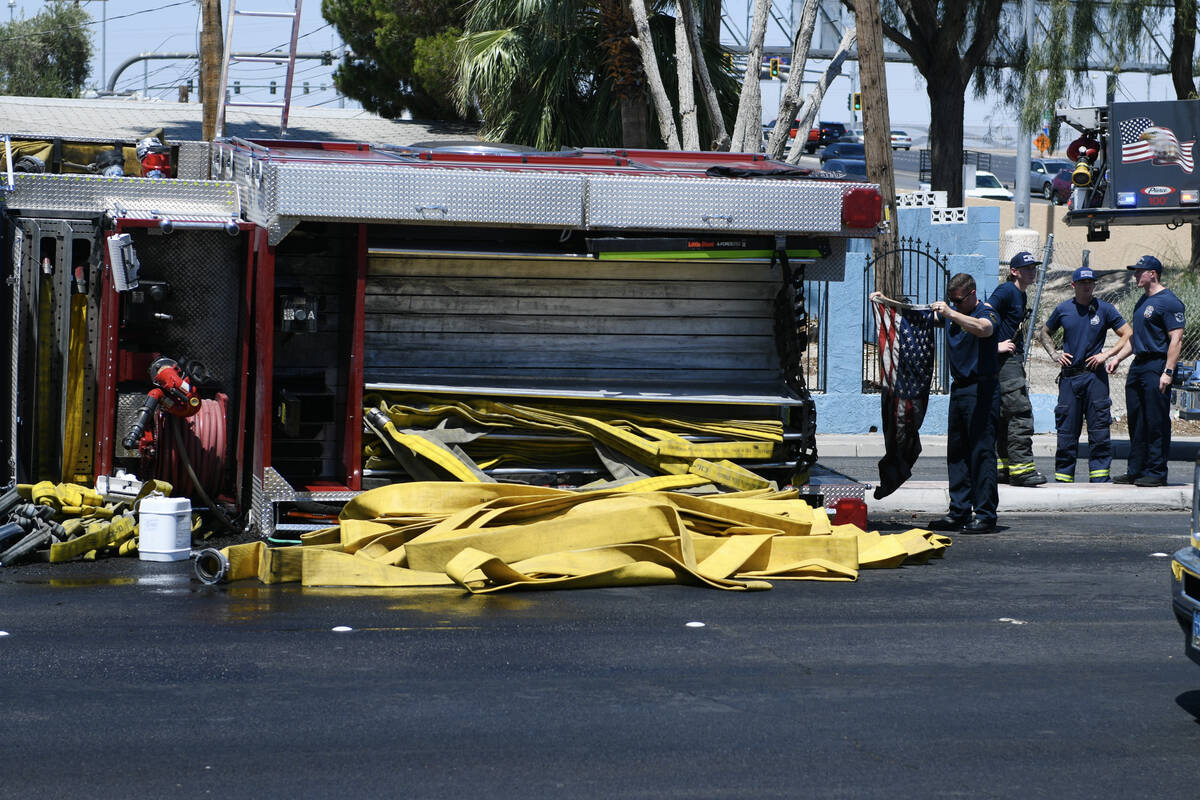 A North Las Vegas retrieves a U.S. flag after a fire truck overturned on Civic Center Drive at ...