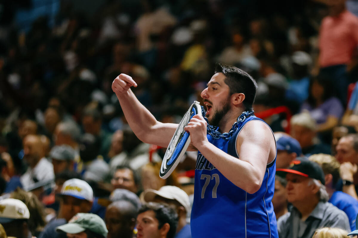 A Dallas Mavericks fan holds up his giant, autographed foam necklace to try and get a shirt fro ...