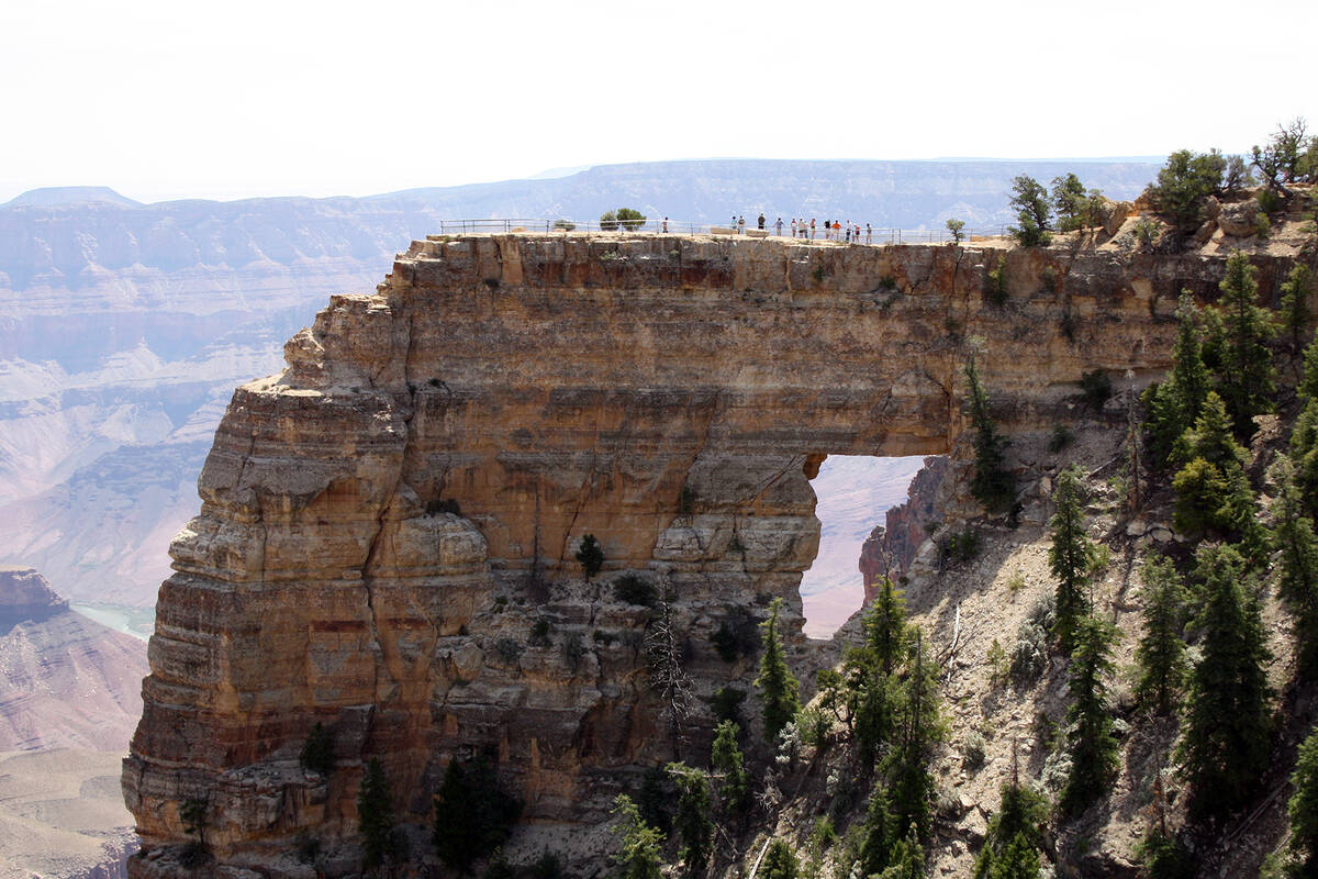 Hikers stand above Angels Window just a five minute hike from Cape Royal Road at the North Rim ...