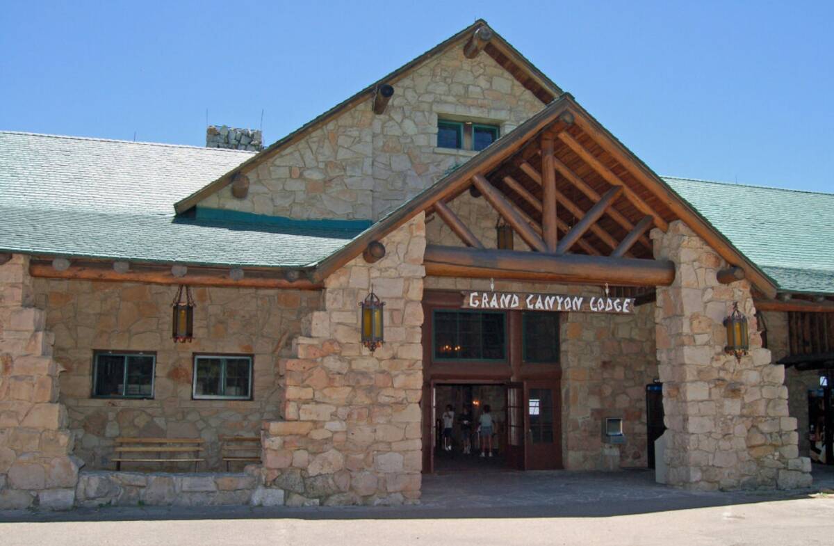 This photo shows the historic Grand Canyon Lodge's front entrance with a sloped roof, huge pond ...
