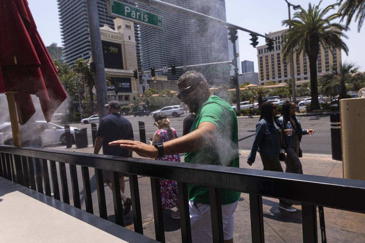 A man cools off by misters along the Las Vegas Strip near Paris Las Vegas as temperatures appro ...
