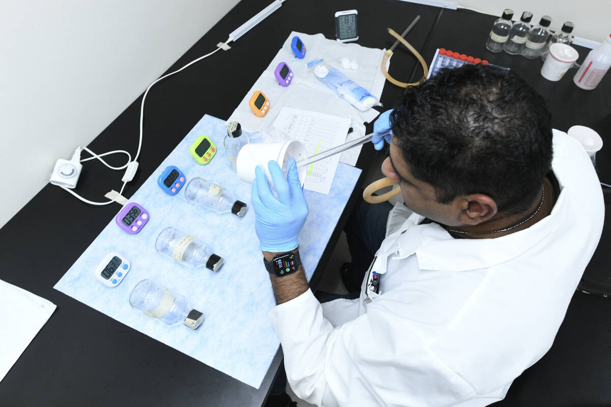 Trishan Wickramasinghe uses a hose to collect mosquitos for an experiment Tuesday, July 15, 202 ...