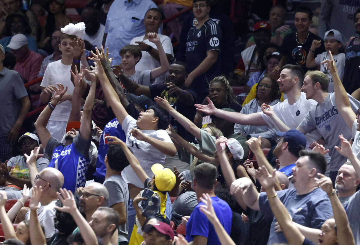 Fans reach to catch a towel from the-towel cannon during the NBA Summer League game between the ...