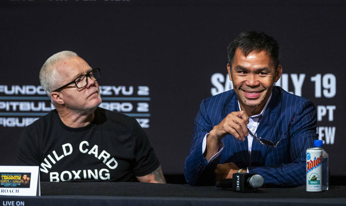 Manny Pacquiao poses for the crowd beside trainer Freddie Roach during a press conference for h ...