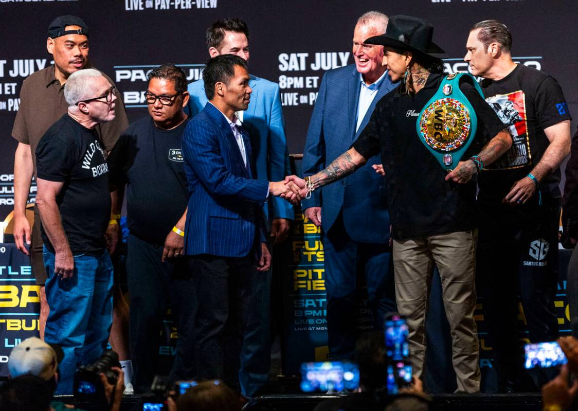 Manny Pacquiao and Mario Barrios shake after their face off for the crowd with their teams and ...