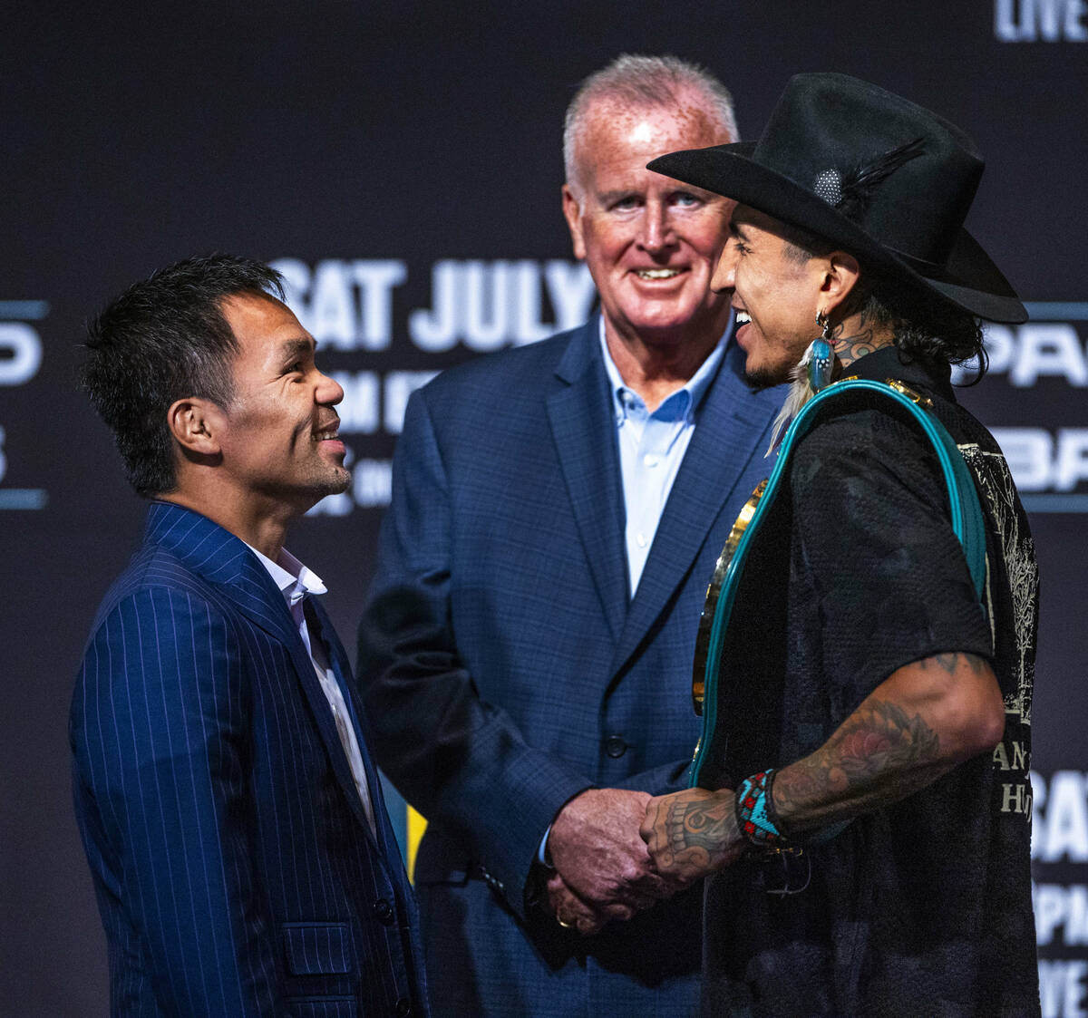 Manny Pacquiao and Mario Barrios face off for the crowd with promoter Tom Brown in between duri ...